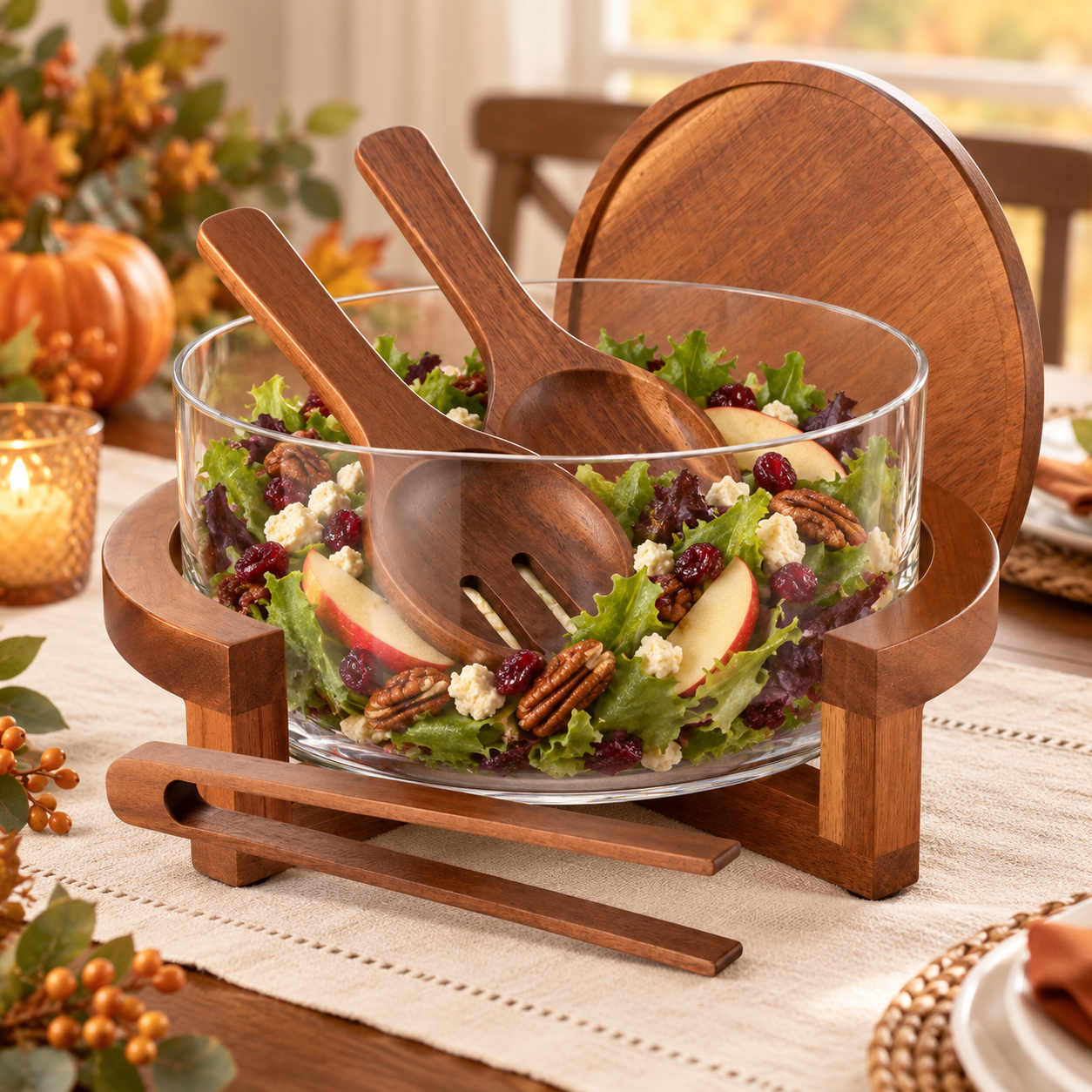 Glass serving bowl filled with fall salad in an acacia wood stand with lid and wooden utensils